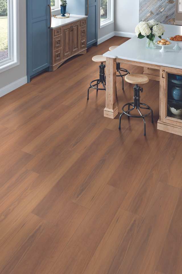 medium toned hardwood floor in modern kitchen with blue accent cupboards and wooden stools